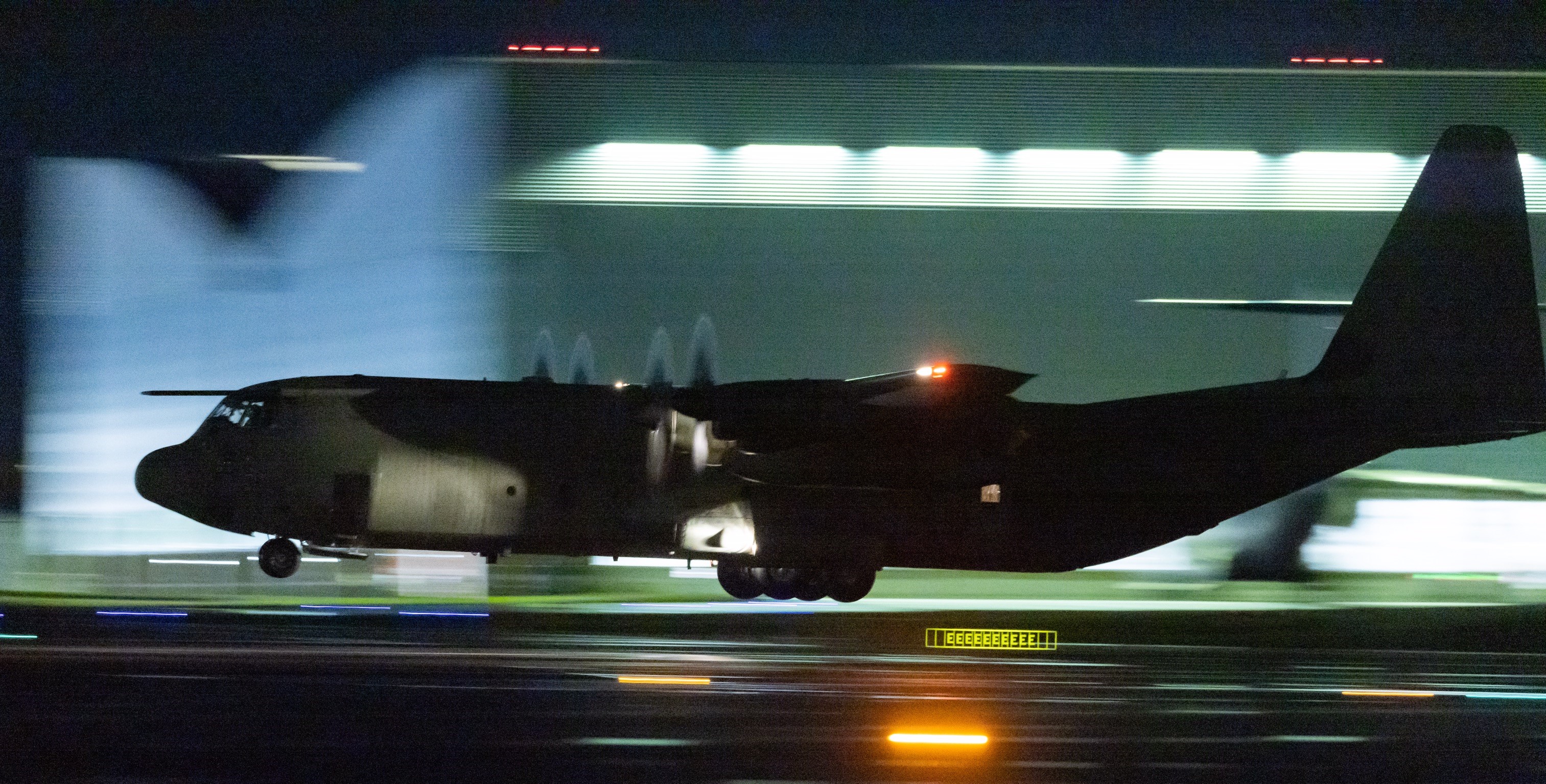 Image shows the RAF Hercules aircraft taxiing on the airstrip at night.
